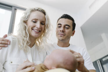 Lächelnde Frau mit Baby, das bei einem Mann zu Hause sitzt - TYF00261