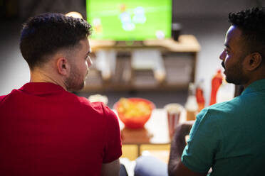 Friends talking with each other watching football match at home - SBAF00107