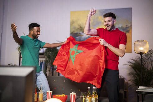 Glückliche Fußballfans mit marokkanischer Flagge jubeln zu Hause - SBAF00112