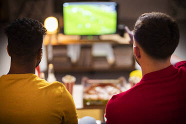 Young roommates watching soccer match at home - SBAF00127