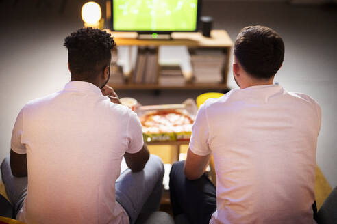 Junge Mitbewohner, die zu Hause gemeinsam ein Fußballspiel ansehen - SBAF00143