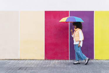 Mädchen mit buntem Regenschirm auf dem Fußweg - PNAF04030