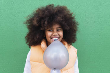 Little girl chewing balloon strings in her mouth Stock Photo by photocreo