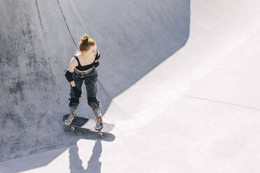 Nachdenklicher Teenager auf dem Skateboard an einem sonnigen Tag - OMIF00893