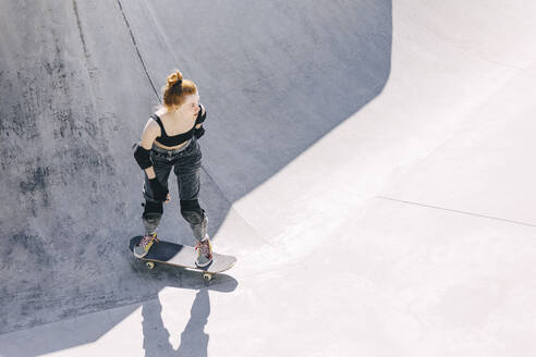 Nachdenklicher Teenager auf dem Skateboard an einem sonnigen Tag - OMIF00893