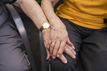 Hände eines älteren Mannes auf dem Schoß einer Frau - SVKF00288