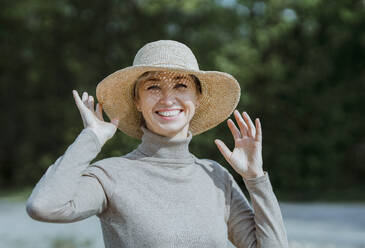 Lächelnde Frau mit Hut genießt den sonnigen Tag - AANF00277