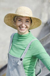 Glückliche Frau mit Hut an einem sonnigen Tag - AANF00304