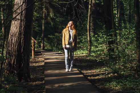 Junge Frau mit geschlossenen Augen auf einem Fußweg im Wald - VPIF06536