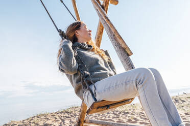 Frau schwingt auf einer Schaukel am Strand - VPIF06554