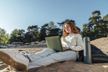 Frau beim E-Learning über Laptop am Strand - VPIF06573