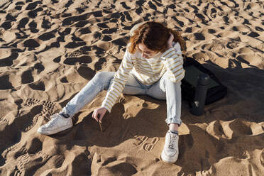 Junge Frau schreibt auf Sand am Strand - VPIF06579