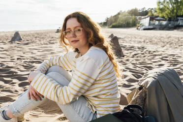 Frau sitzt am Strand an einem sonnigen Tag - VPIF06581