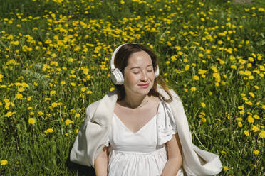 Schwangere Frau sitzt inmitten von Pflanzen an einem sonnigen Tag - SEAF01000