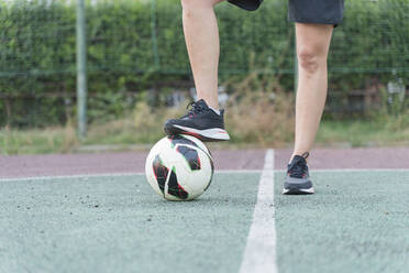 Frau mit Bein auf Fußball im Sportplatz - FMOF01522