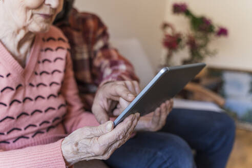 Älterer Mann unterrichtet ältere Frau zu Hause in Tablet-PC - OSF00064