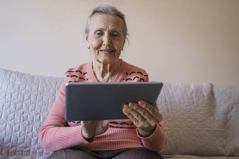 Glückliche ältere Frau, die einen Tablet-PC im Wohnzimmer benutzt - OSF00068