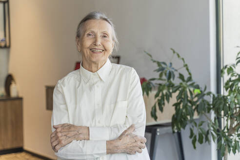 Selbstbewusste ältere Frau mit verschränkten Armen in einem Café - OSF00087
