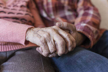 Mature man holding hands of senior woman at home - OSF00093