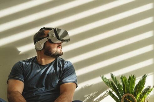 Mann schaut durch eine VR-Brille vor einer Wand - OSF00100