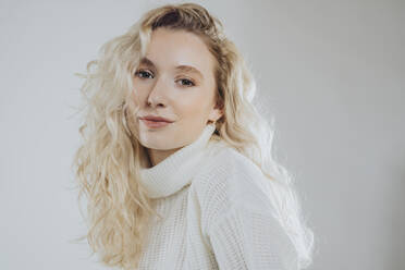 Young blond woman wearing turtleneck against white background - MFF09121
