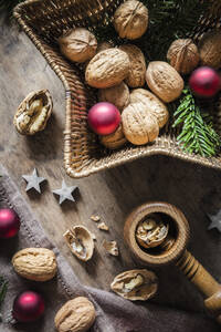 Studioaufnahme von Schneidebrett, sternförmigem Weidenkorb, Weihnachtsschmuck, Walnüssen und einfachem Nussknacker - EVGF04027