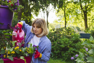 Woman watering flowers with watering can in garden - IHF00913