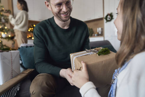 Lächelndes Mädchen schenkt seinem Vater zu Hause ein Weihnachtsgeschenk - ABIF01715