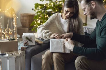 Happy woman with man wrapping Christmas gift at home - ABIF01719