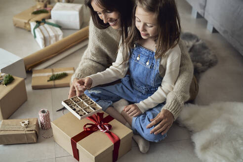 Lächelndes Mädchen und Mutter mit Dekoration Box Verpackung Geschenk zu Hause - ABIF01743