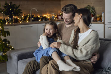 Smiling girl with parents enjoying in living room - ABIF01750