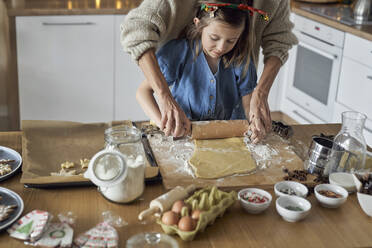 Mother helping daughter in rolling cookie dough - ABIF01773