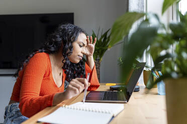 Stressed woman focusing on work using laptop at home office - WPEF05989