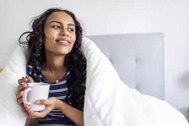 Nachdenkliche Frau, die in eine Decke eingewickelt Kaffee genießt - WPEF06029