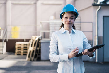 Smiling female architect in work helmet with tablet PC at factory - JOSEF10525