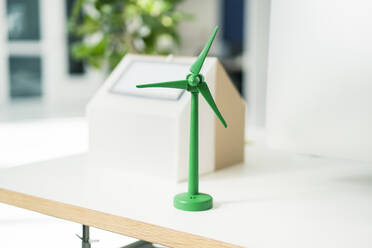 Modell einer Windkraftanlage und eines Hauses mit Sonnenkollektoren auf einem Schreibtisch im Büro - JOSEF10544