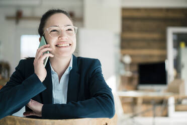 Glückliche Geschäftsfrau im Gespräch am Telefon am Arbeitsplatz - JOSEF10556