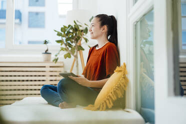 Nachdenkliche Frau mit Tablet-PC im Wohnzimmer - JOSEF10568