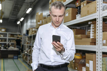 Businessman using smart phone in factory - EYAF01951