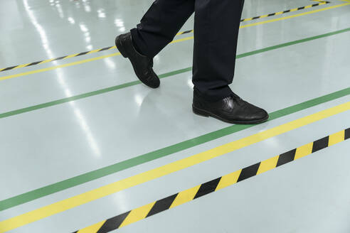 Geschäftsmann überquert Linie auf dem Boden in der Fabrik - EYAF01958