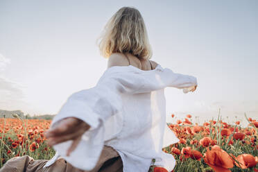 Woman with arms outstretched in poppy field - SIF00191