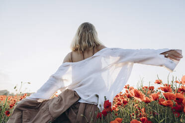 Carefree woman spinning in poppy field - SIF00192