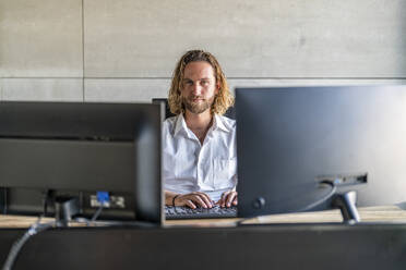 Selbstbewusste Führungskraft mit Computer am Schreibtisch im Büro - DLTSF02951