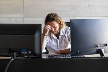 Depressiver Geschäftsmann mit Kopf in der Hand am Schreibtisch - DLTSF02954