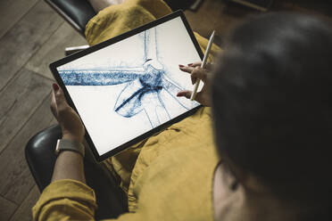 Engineer pinching design of wind turbine on graphics tablet at home office - UUF26478