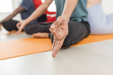 Hand eines Mannes, der mit Freunden im Yogastudio meditiert - OSF00115