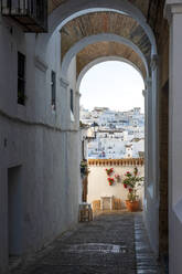 Spanien, Provinz Cádiz, Vejer de la Frontera, Bogengang mit Häusern im Hintergrund - NDF01471