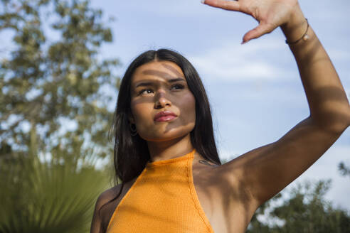Young woman shielding face from sunlight - PGCF00116