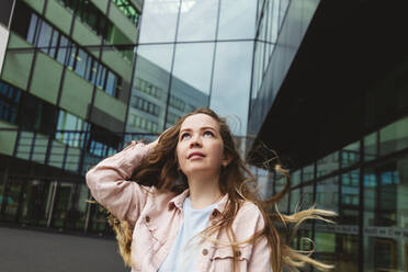 Smiling woman with brown hair standing in front of building - IHF00933