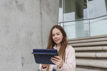 Lächelnde junge Frau mit Tablet-PC auf einer Treppe sitzend - IHF00941